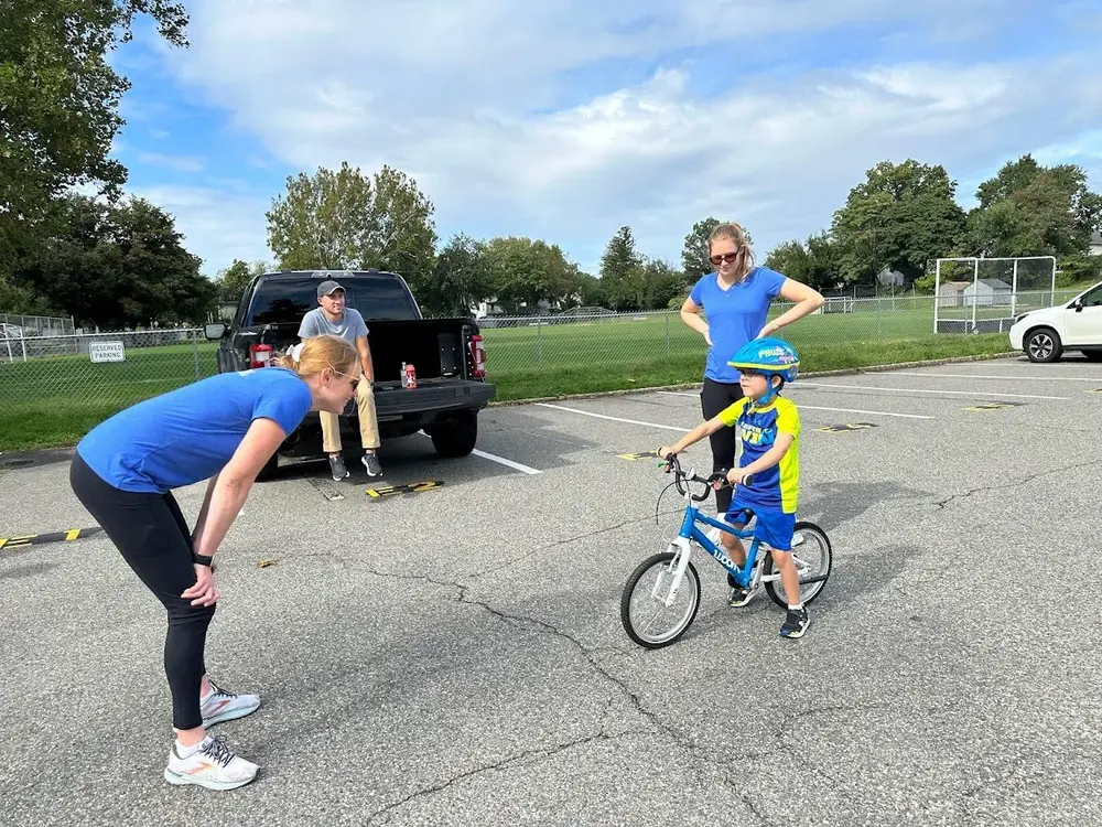 An instructor adapting one-on-one bike coaching to a child
