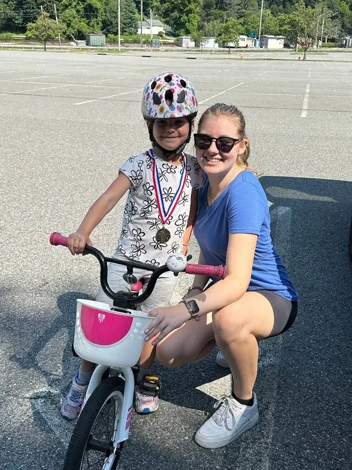 A smiling child with a bike and a Ready to Pedal instructor after a lesson
